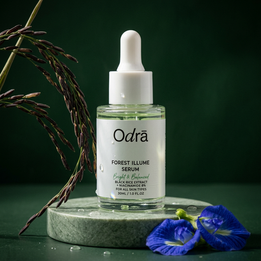 Forest Illume Serum bottle on sage stone plinth with black rice and blue pea flowers