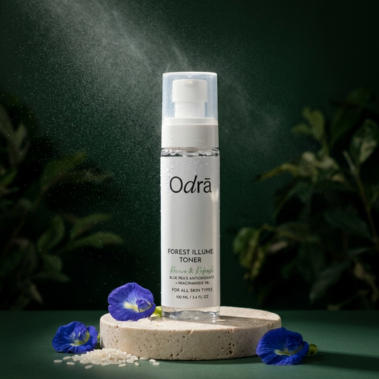 Forest Illume Toner clear glass bottle on travertine pedestal with blue pea flowers and mist